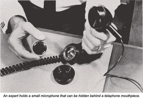 An expert holds a small microphone that can be hidden behind a telephone mouthpiece.